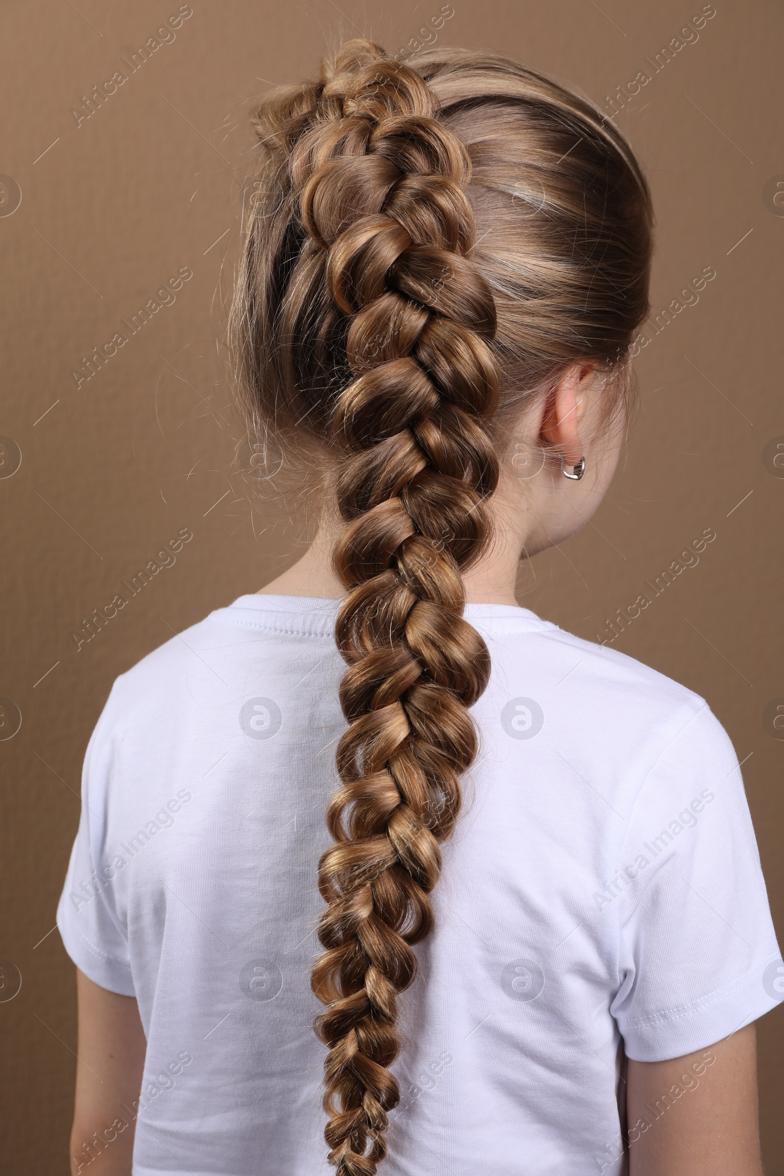 Photo of Little girl with braided hair on light brown background, back view