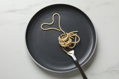 Photo of Heart made of tasty spaghetti and fork on white marble table, top view