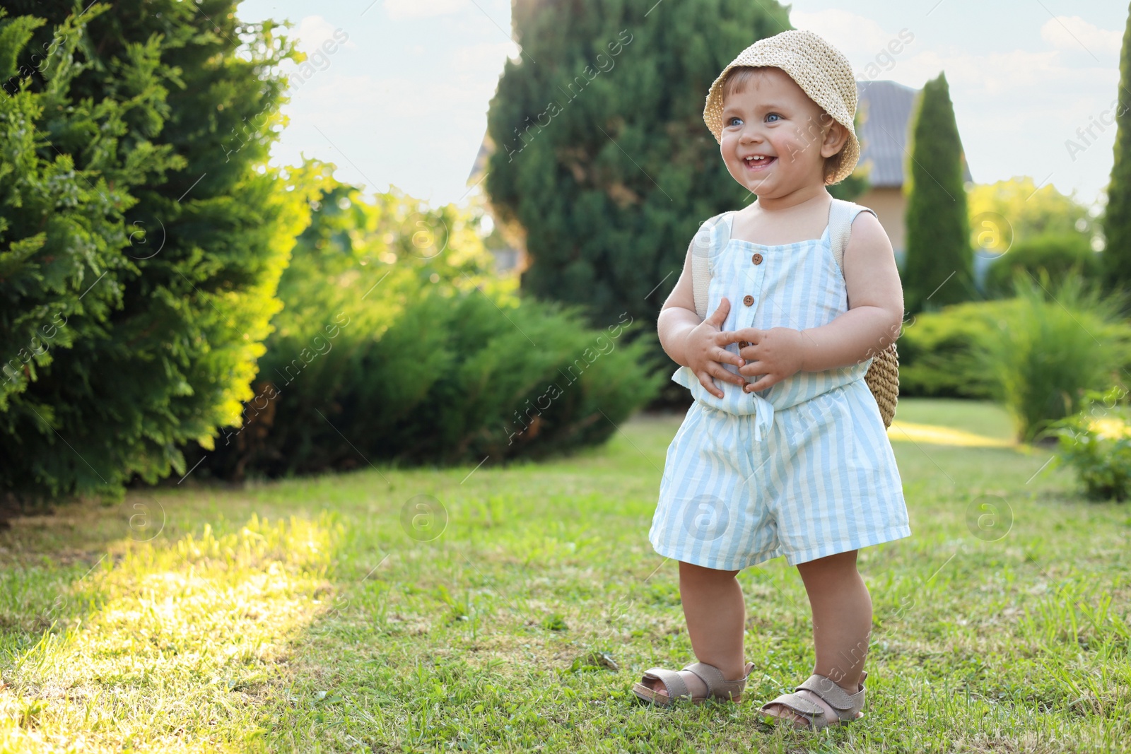 Photo of Cute little girl wearing stylish clothes outdoors on sunny day. Space for text