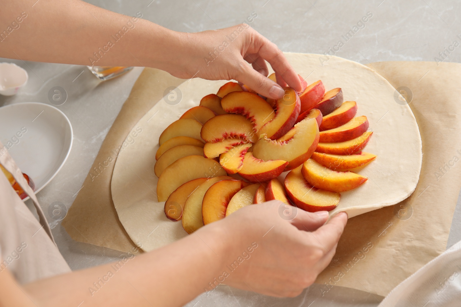 Photo of Woman making peach pie at table, closeup