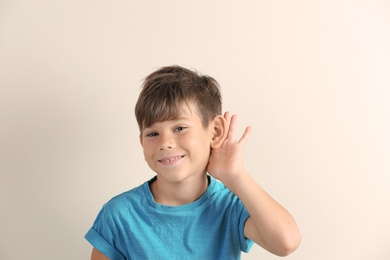 Photo of Cute little boy with hearing problem on light background