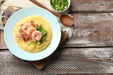 Photo of Plate with fresh tasty shrimps, bacon, grits and green onion on wooden table, flat lay. Space for text
