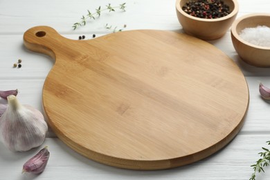 Photo of Cutting board and different spices on white wooden table