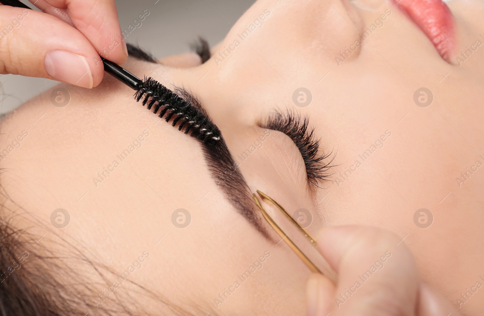 Photo of Young woman having professional eyebrow correction procedure, closeup