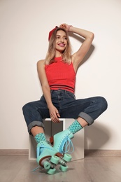 Photo of Young woman with retro roller skates against light wall