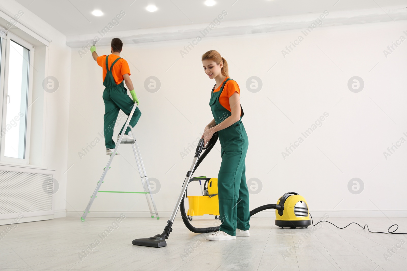 Photo of Professional young janitor vacuuming indoors. Cleaning service