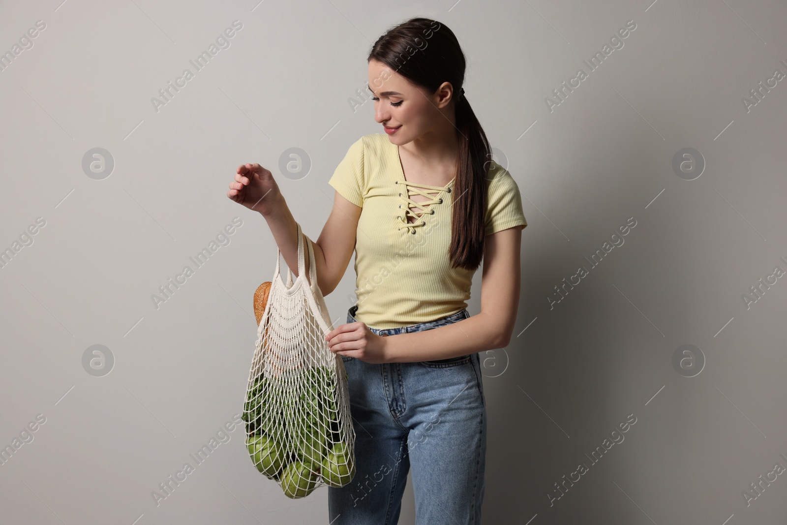 Photo of Woman with eco bag full of products on light background