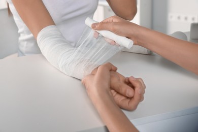 Photo of Doctor applying bandage onto patient's arm in hospital, closeup