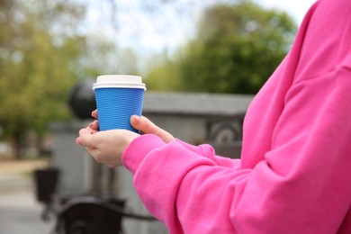 Photo of Woman with takeaway coffee cup outdoors, closeup. Space for text