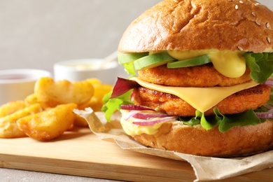 Photo of Board with double vegetarian burger and fried potatoes on table, closeup