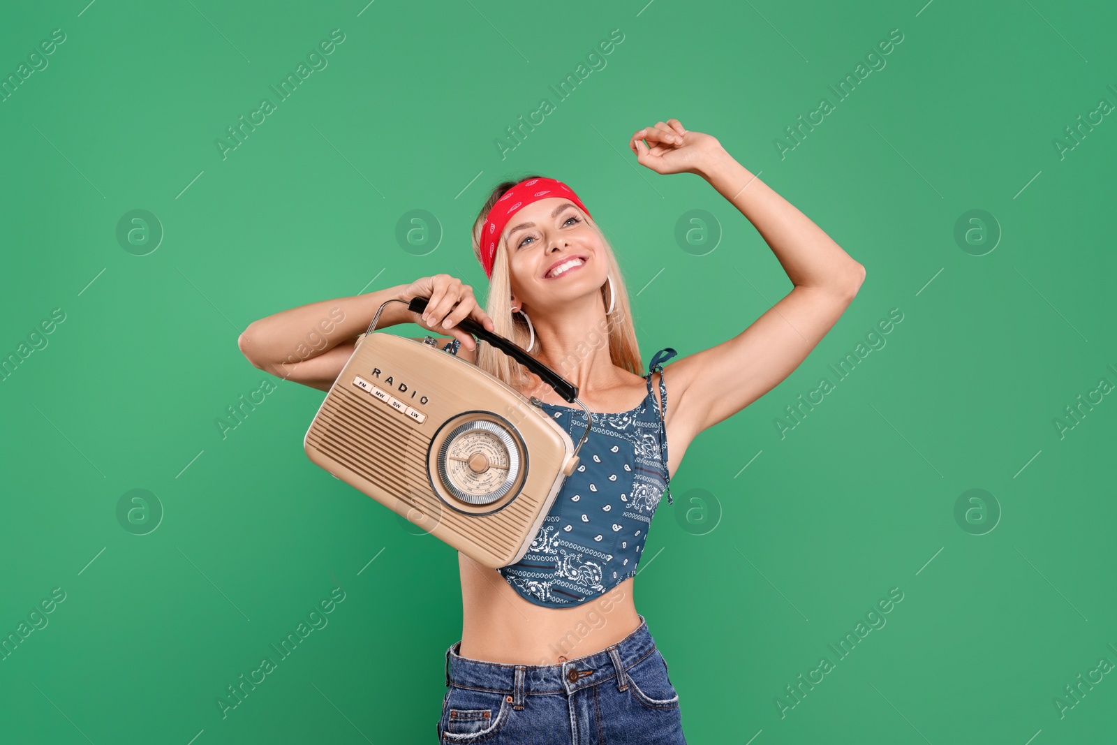 Photo of Happy hippie woman with retro radio receiver dancing on green background