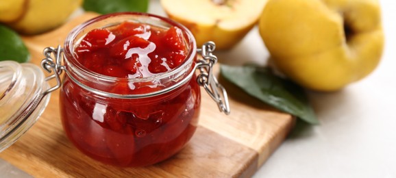 Image of Delicious quince jam on light grey table, closeup. Banner design