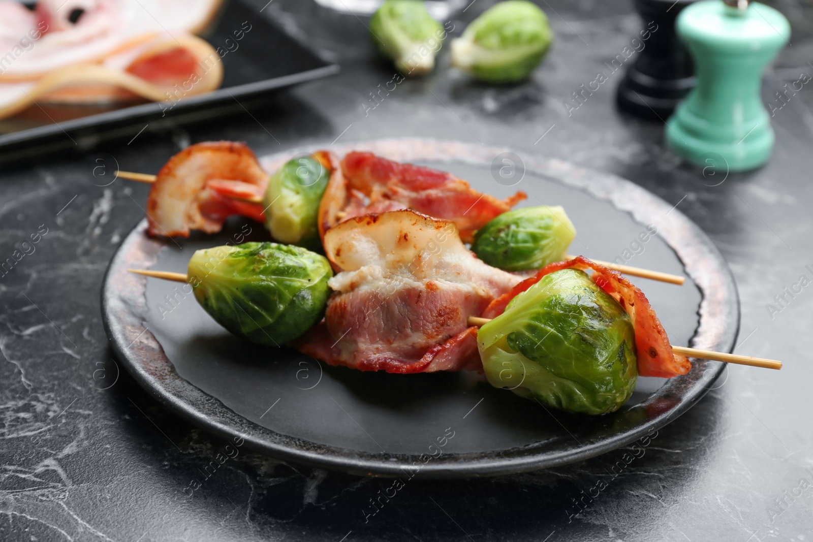 Photo of Skewers with Brussels sprouts and bacon served on marble table