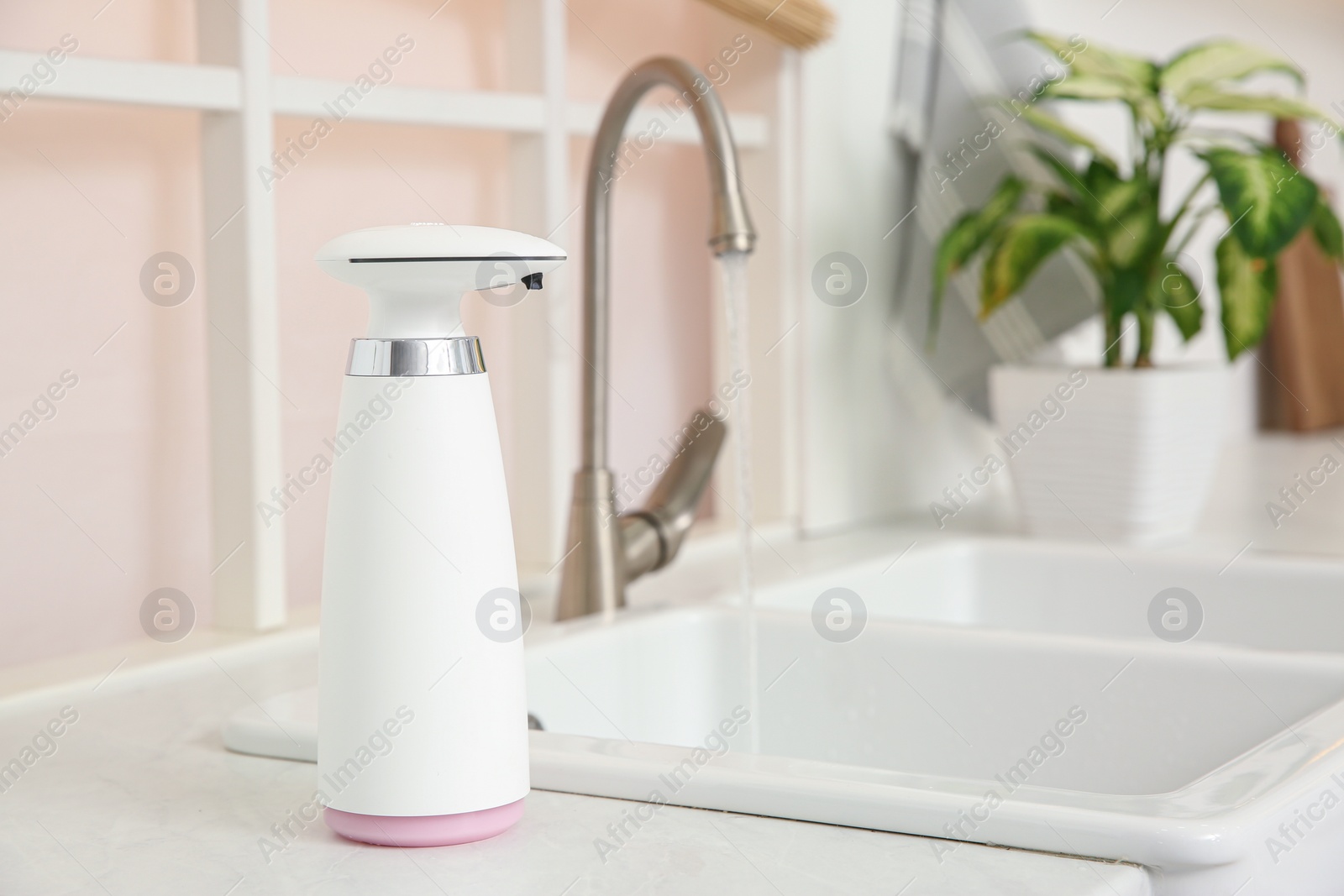 Photo of Modern automatic soap dispenser on countertop in kitchen. Space for text