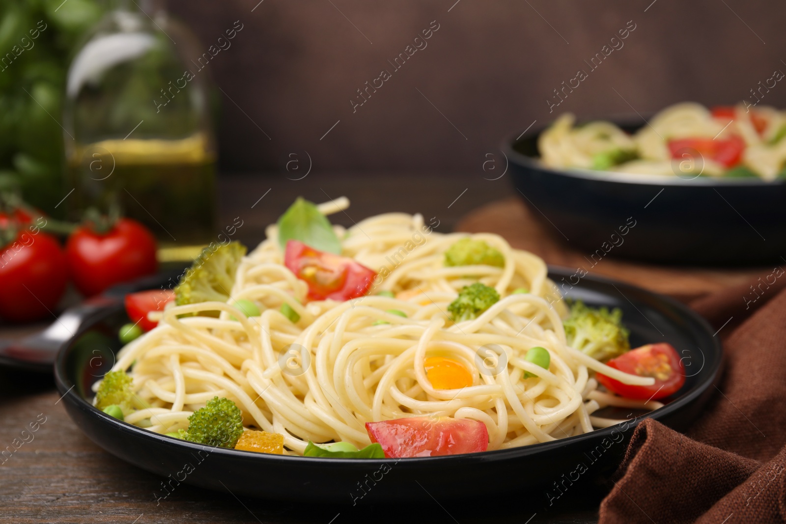 Photo of Plate of delicious pasta primavera and ingredients on table, closeup