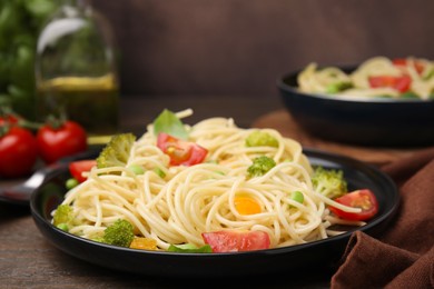 Plate of delicious pasta primavera and ingredients on table, closeup