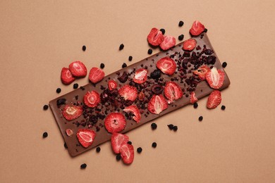 Chocolate bar with freeze dried fruits on beige background, top view