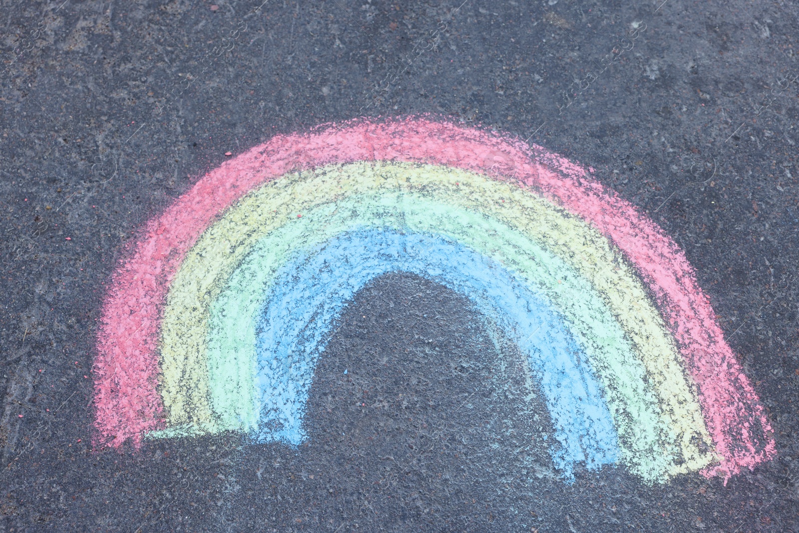 Photo of Child's chalk drawing of rainbow on asphalt, above view