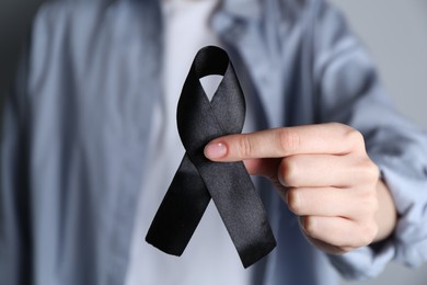 Woman holding black awareness ribbon, closeup view