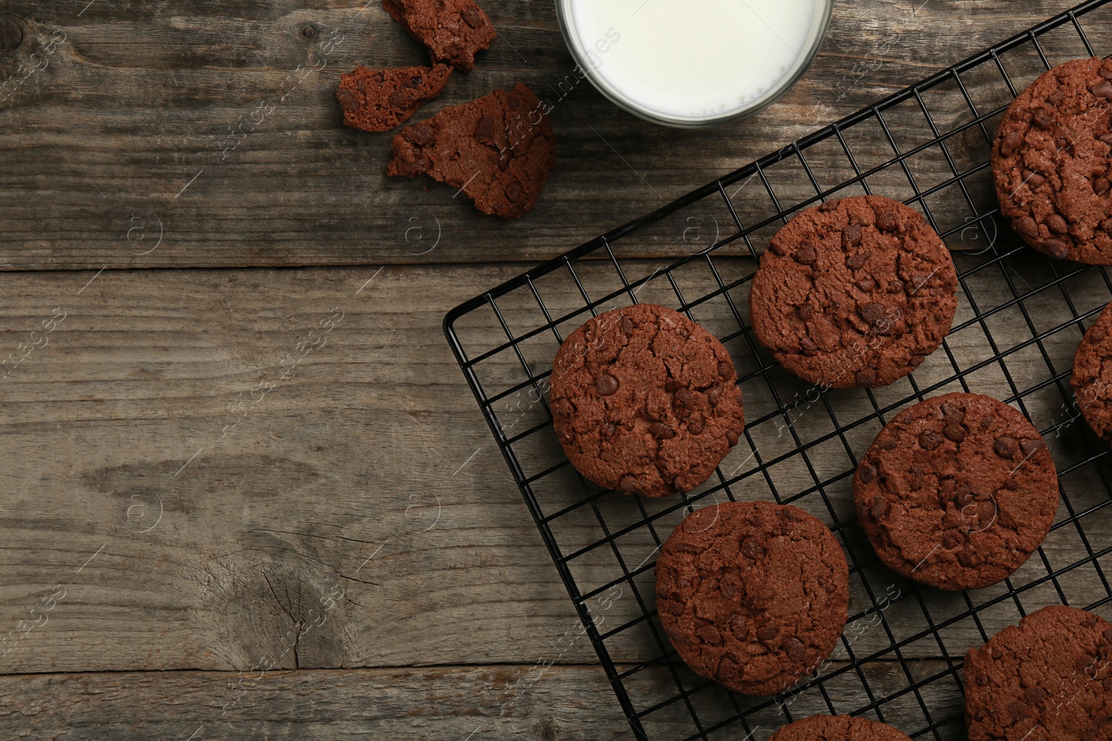 Photo of Delicious chocolate chip cookies and milk on wooden table, flat lay. Space for text