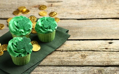 Photo of St. Patrick's day party. Tasty cupcakes with clover leaf toppers and green cream on wooden table. Space for text