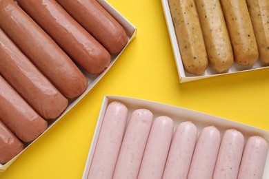 Different vegan sausages on yellow background, flat lay