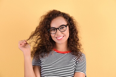 Portrait of laughing African-American woman with glasses on color background