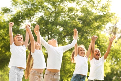 Photo of Group of children holding hands up in park. Volunteer project