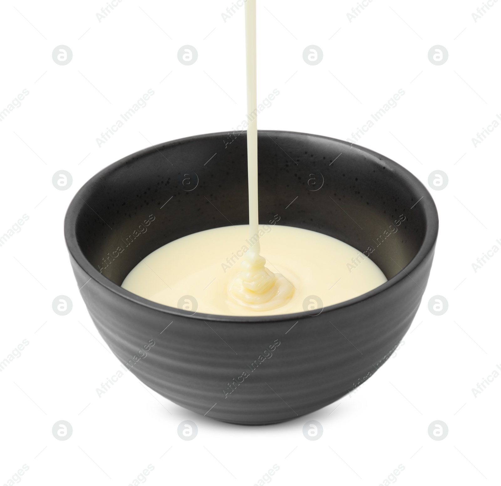 Photo of Pouring condensed milk into bowl isolated on white