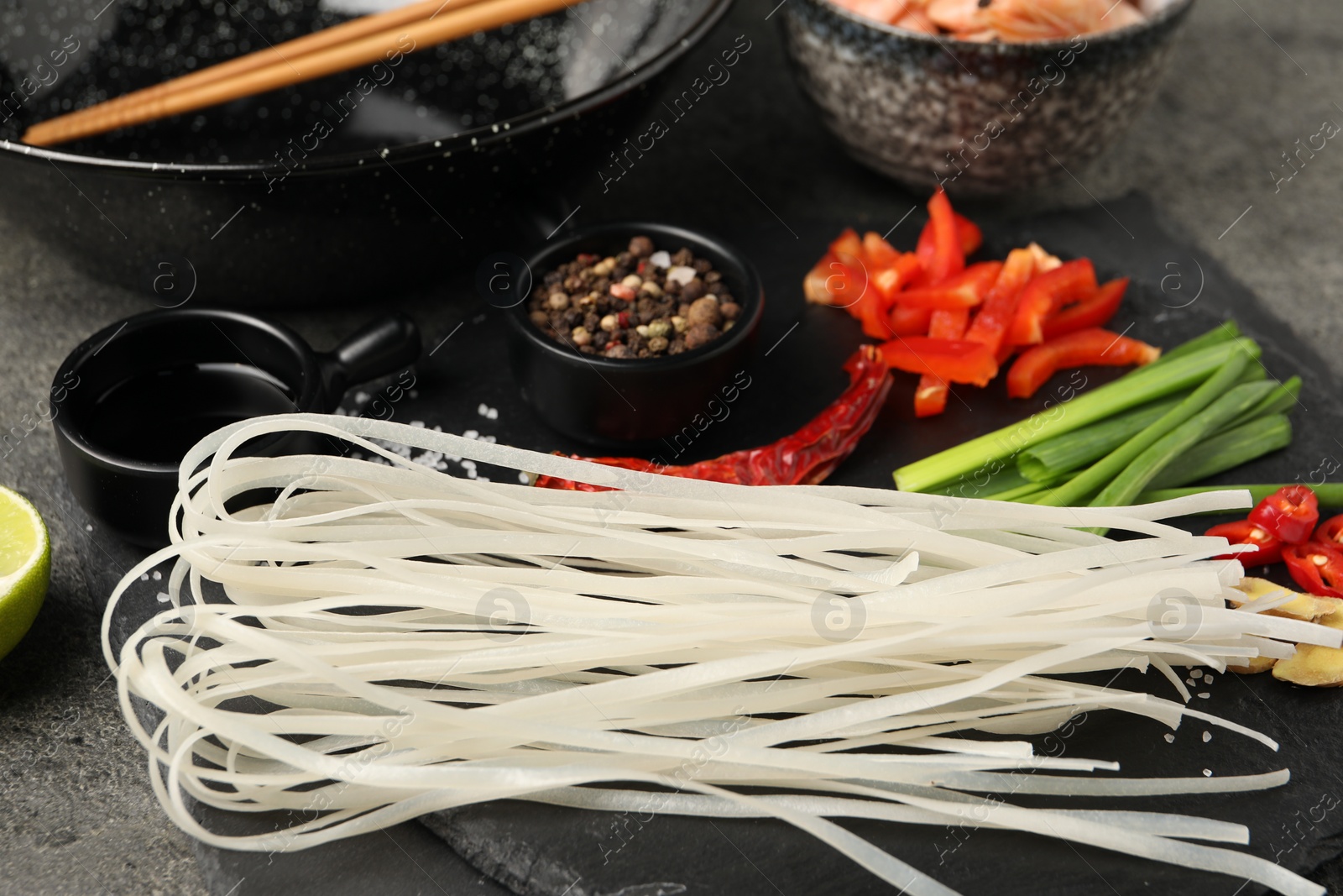 Photo of Different products and wok with chopsticks on dark table, closeup