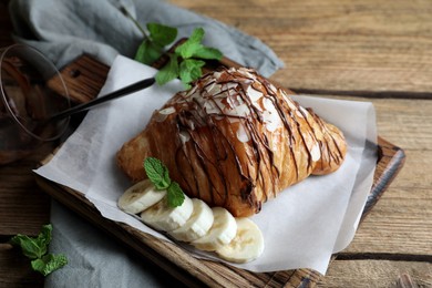 Delicious croissant with chocolate and banana on wooden table
