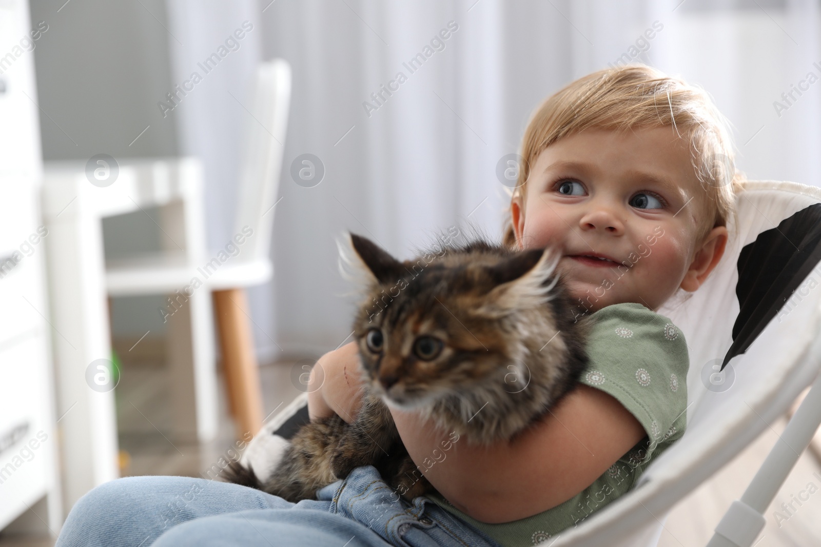 Photo of Cute little child with adorable pet sitting in armchair at home