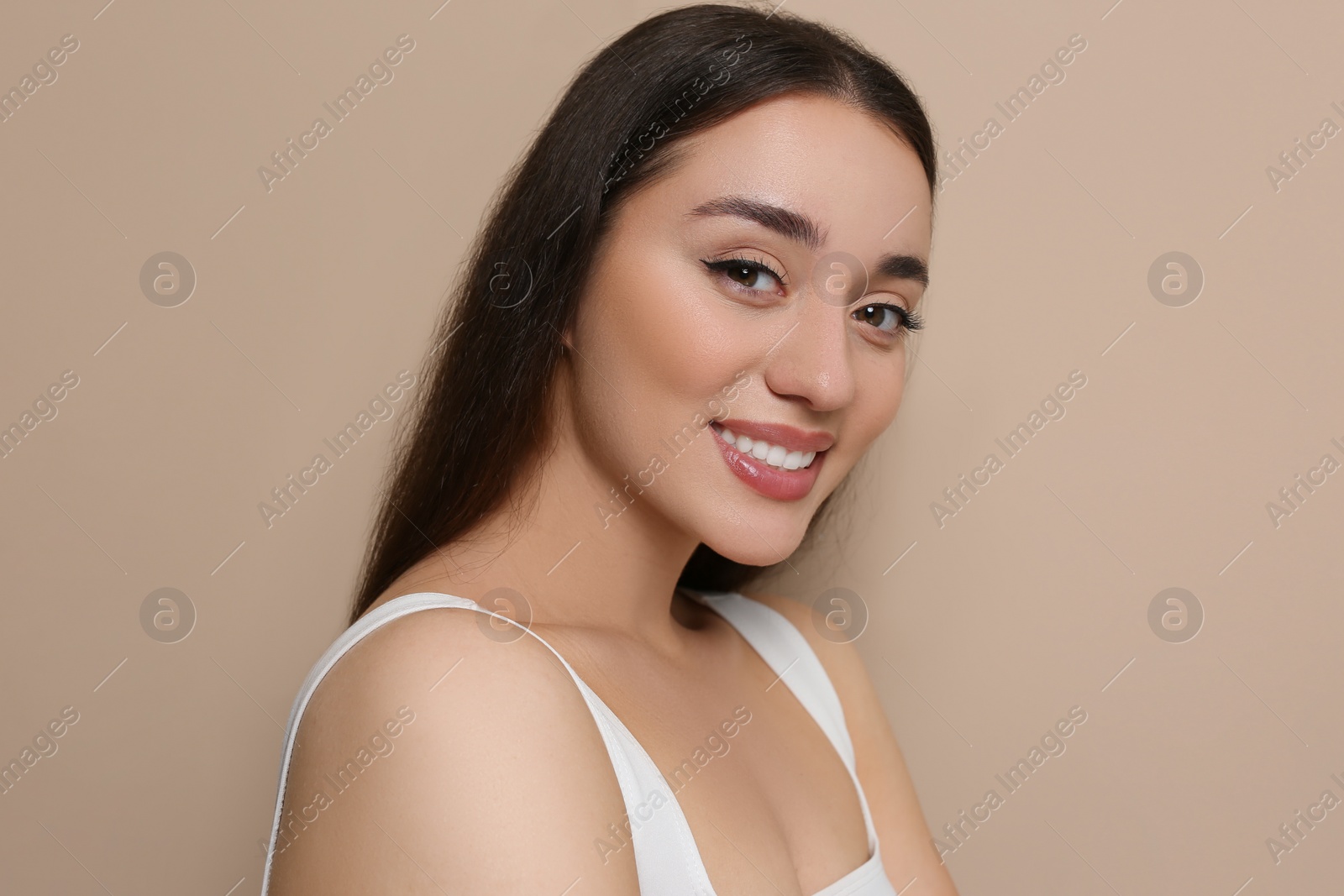 Photo of Portrait of beautiful young woman with elegant makeup on dark beige background