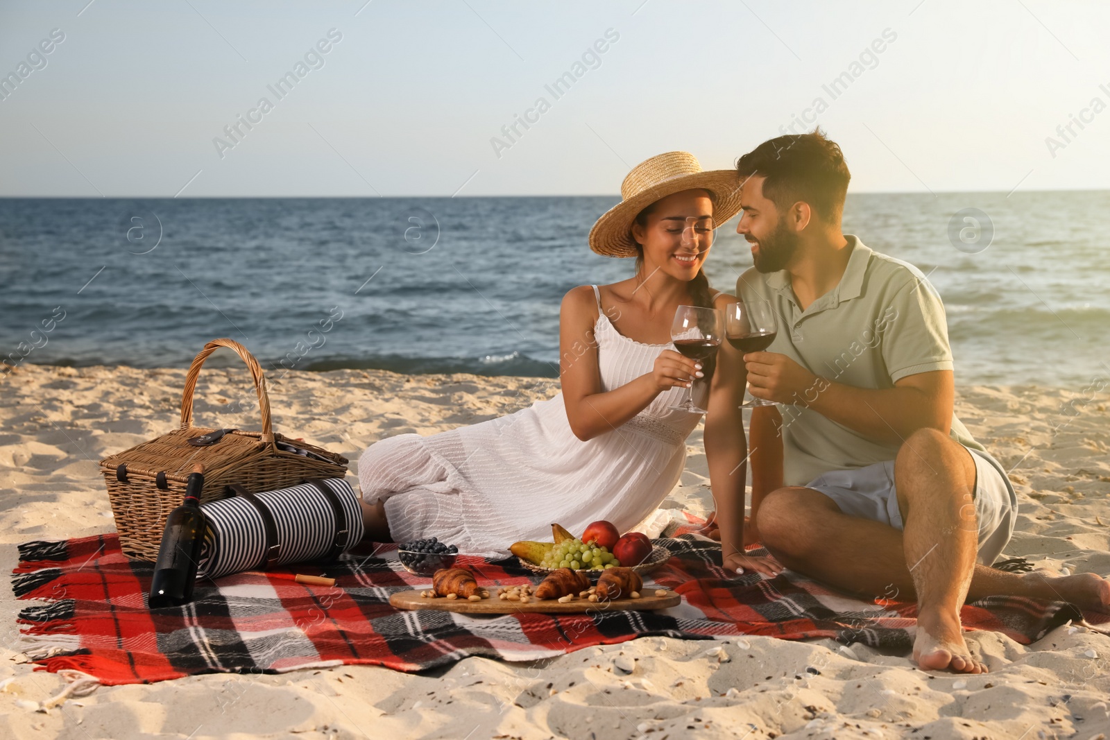 Photo of Lovely couple having picnic on sandy beach near sea