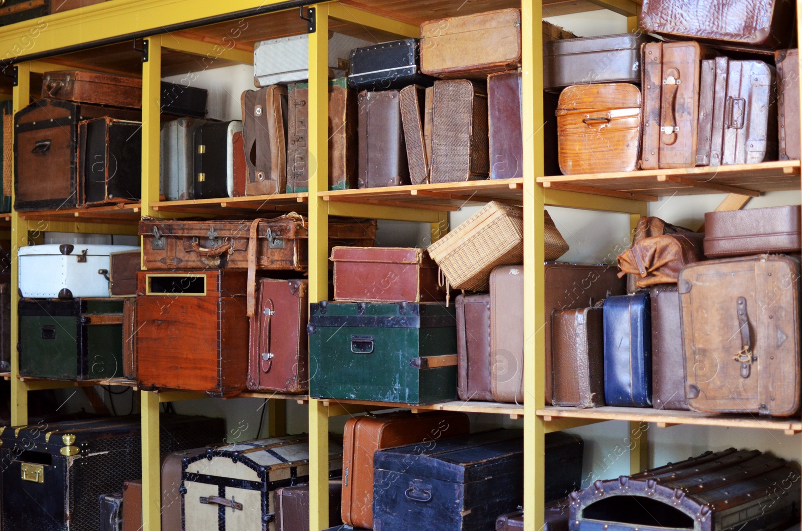 Photo of Many beautiful retro suitcases on shelves indoors