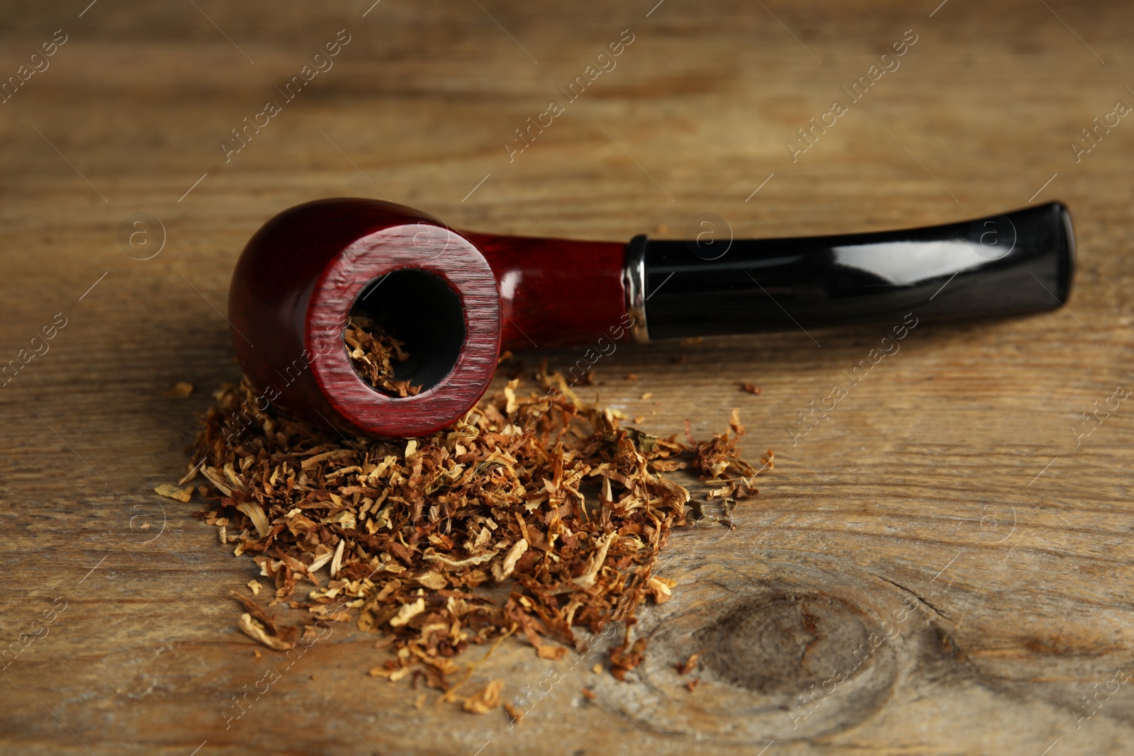 Photo of Classic smoking pipe with tobacco on wooden table