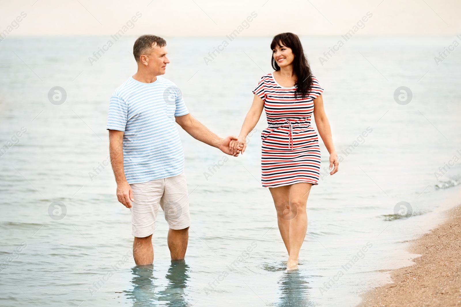 Photo of Happy mature couple walking together on sea beach