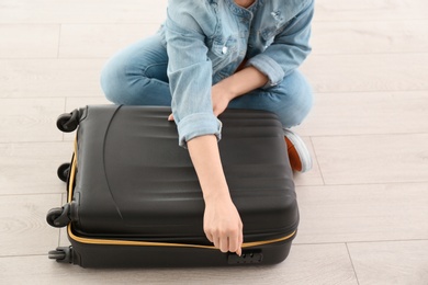Photo of Young woman with suitcase indoors