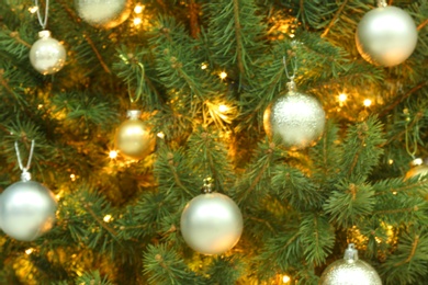 Blurred view of glowing fairy lights and beautiful baubles on Christmas tree