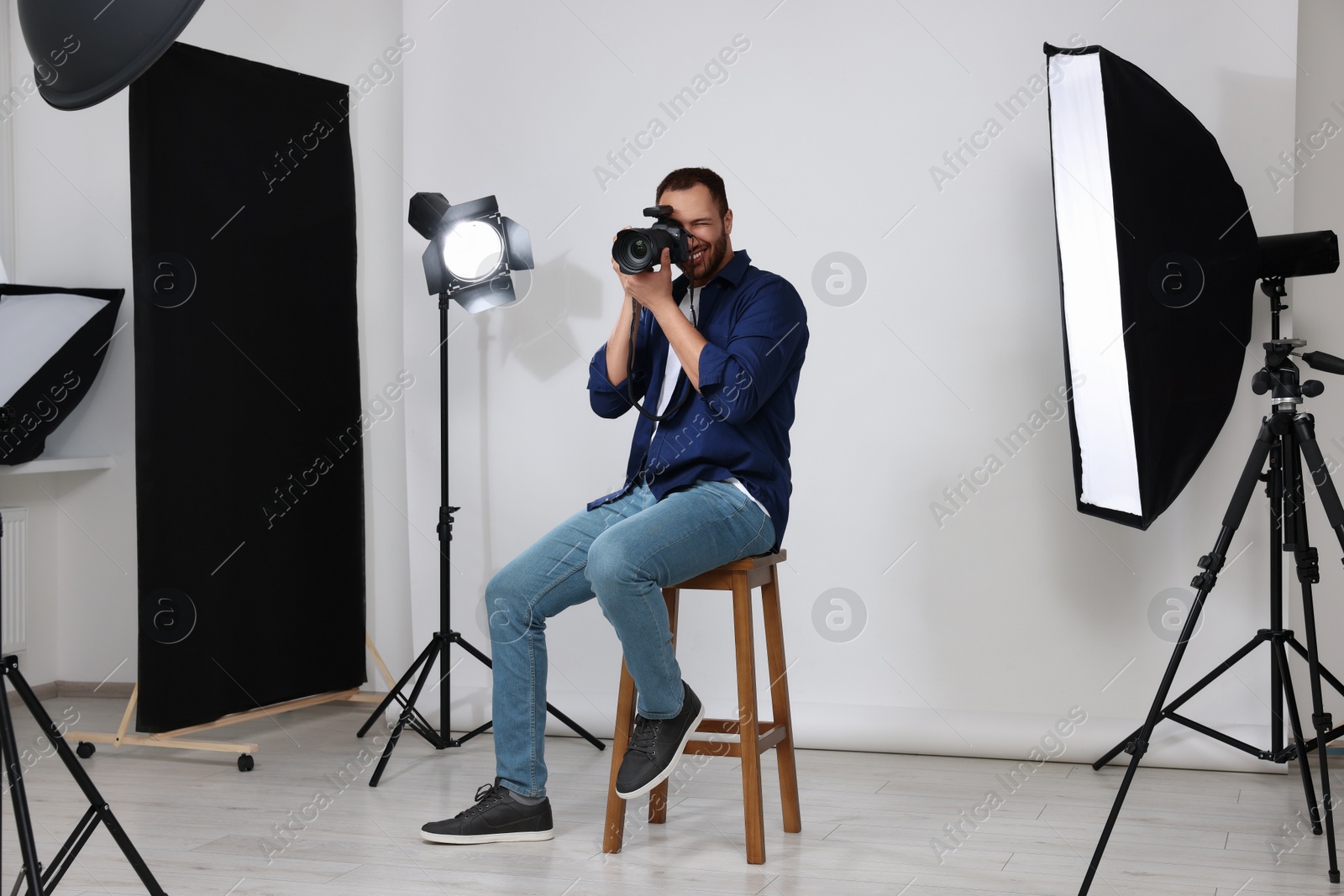 Photo of Young professional photographer taking picture in modern photo studio