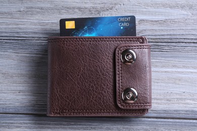 Credit card in leather wallet on grey wooden table, top view