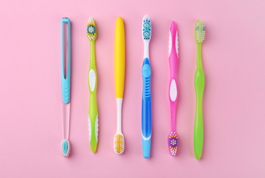 Photo of Many different toothbrushes on pink background, flat lay