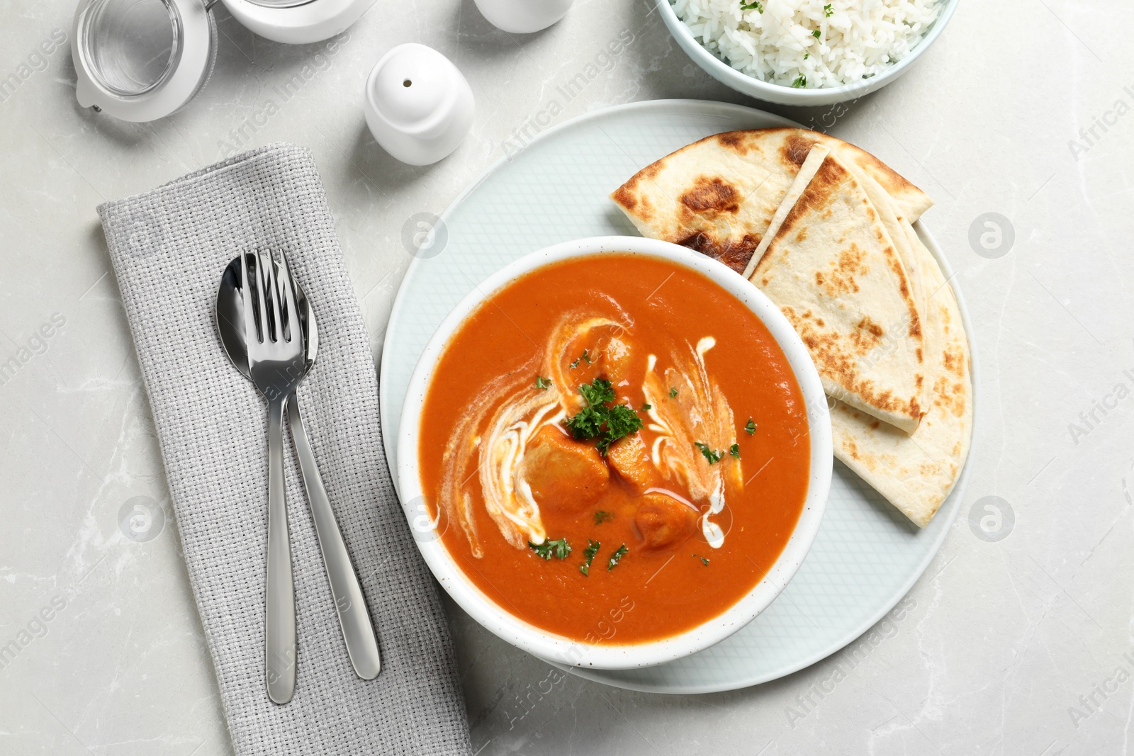 Photo of Delicious butter chicken served on grey table, top view. Traditional Murgh Makhani dish