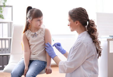 Photo of Little girl receiving chickenpox vaccination in clinic. Varicella virus prevention