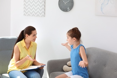 Young female psychologist working with little child in office