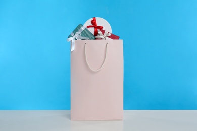 Photo of Paper shopping bag full of gift boxes on light blue background