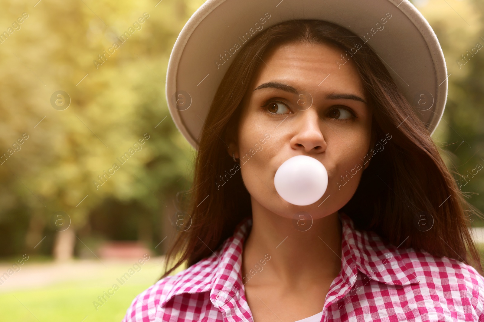 Photo of Beautiful young woman blowing chewing gum outdoors