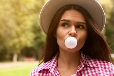 Photo of Beautiful young woman blowing chewing gum outdoors