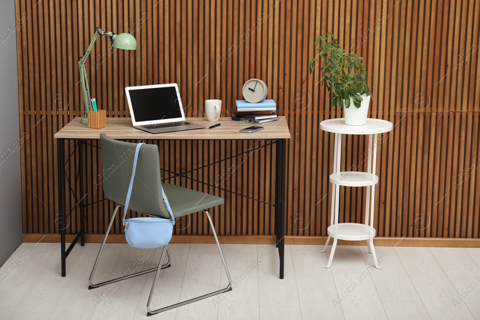 Photo of Stylish workplace interior with laptop on table near wooden wall. Space for text