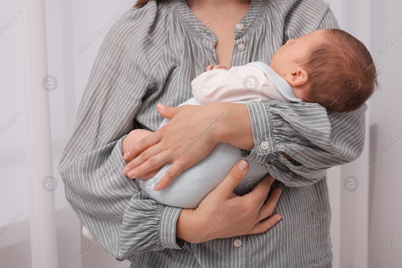 Photo of Mother holding her cute newborn baby indoors, closeup